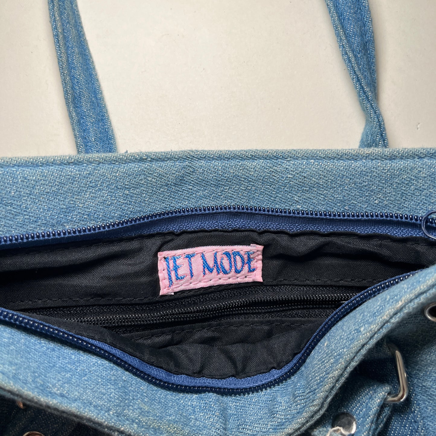 Sac baguette en denim à oeillets métalliques.